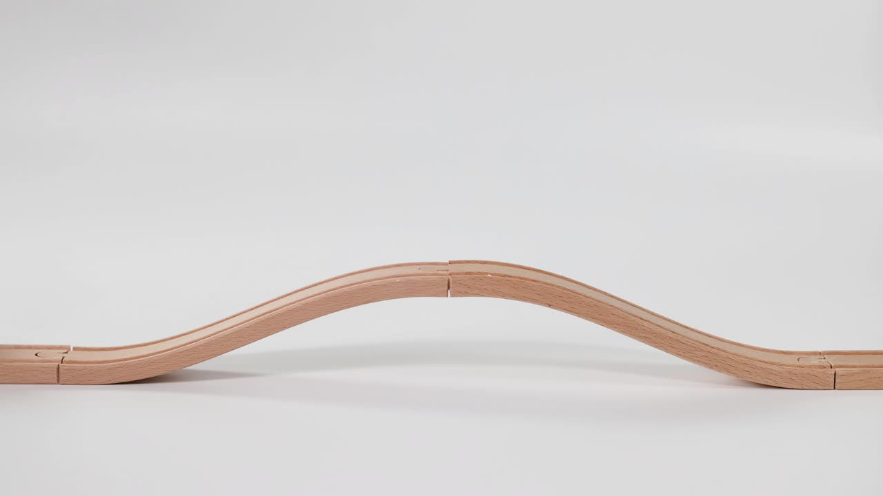 손은 물결 모양의 나무 트랙에서 장난감 차를 움직인다