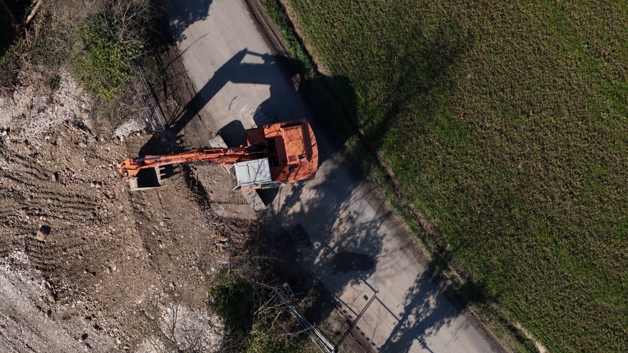 Drone captures an excavator working on a construction site, moving earth and debris with its bucket