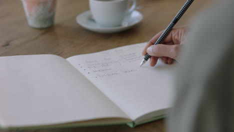 young woman hands writing to do list making notes in diary planning using journal reminder in coffee shop close up