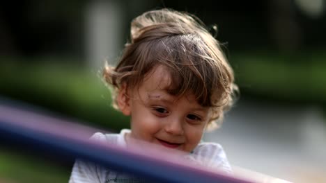 niño despreocupado girando en el carrusel del patio de recreo rostro sonriente de primer plano