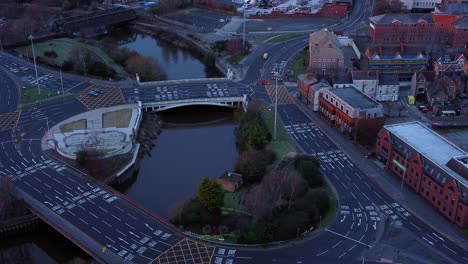 aerial early morning city street traffic commuting intersection lanes crossing curved river slow descent