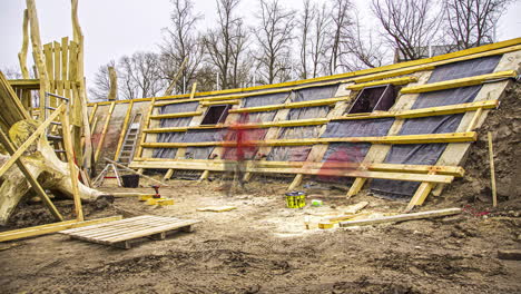 Static shot of workers clearing land and putting wooden ply while putting foundation after digging on a cloudy day