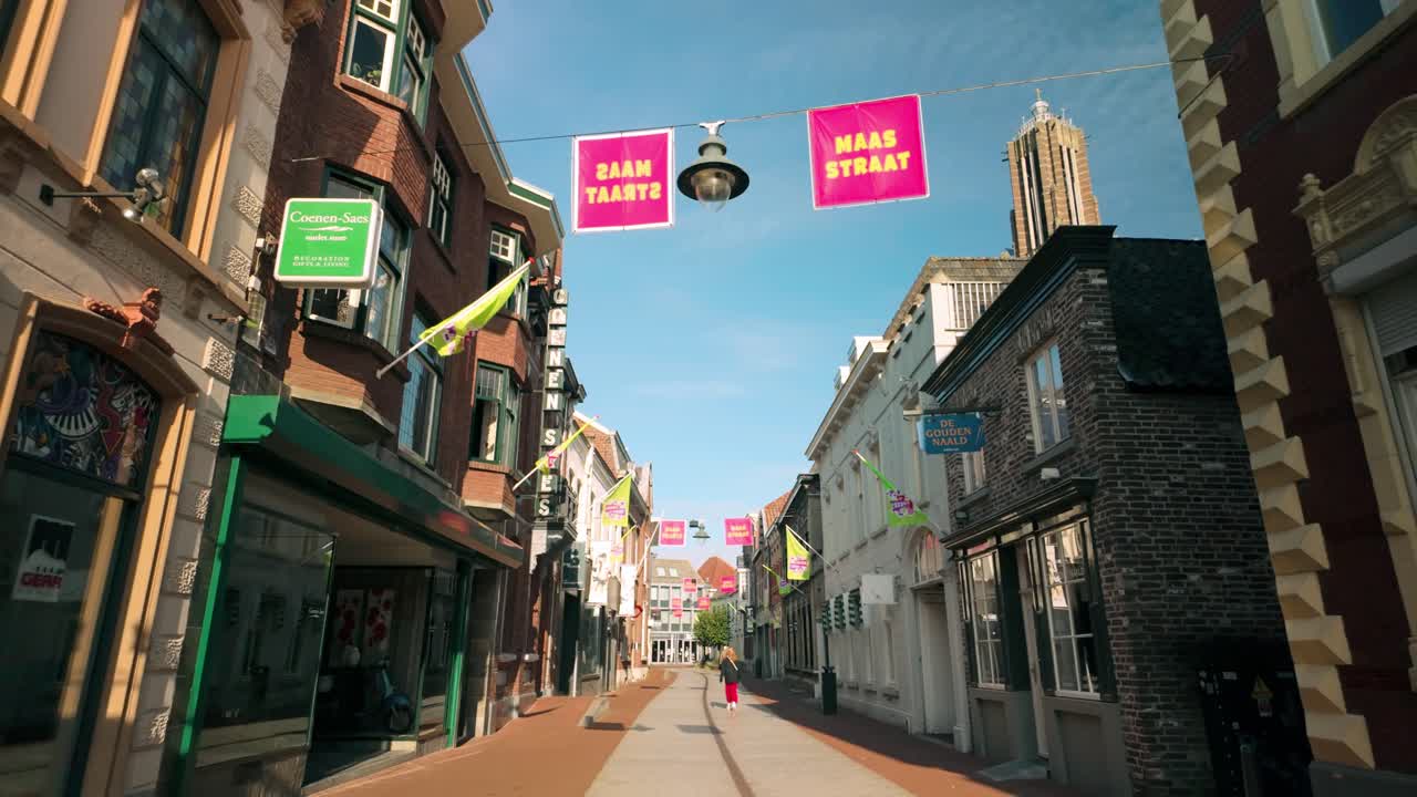 Serene view of Maasstraat shopping street in Weert, Limburg, during an early morning. The street is empty, showcasing the charming architecture and bright signs. Location: Weert, Limburg, Netherlands