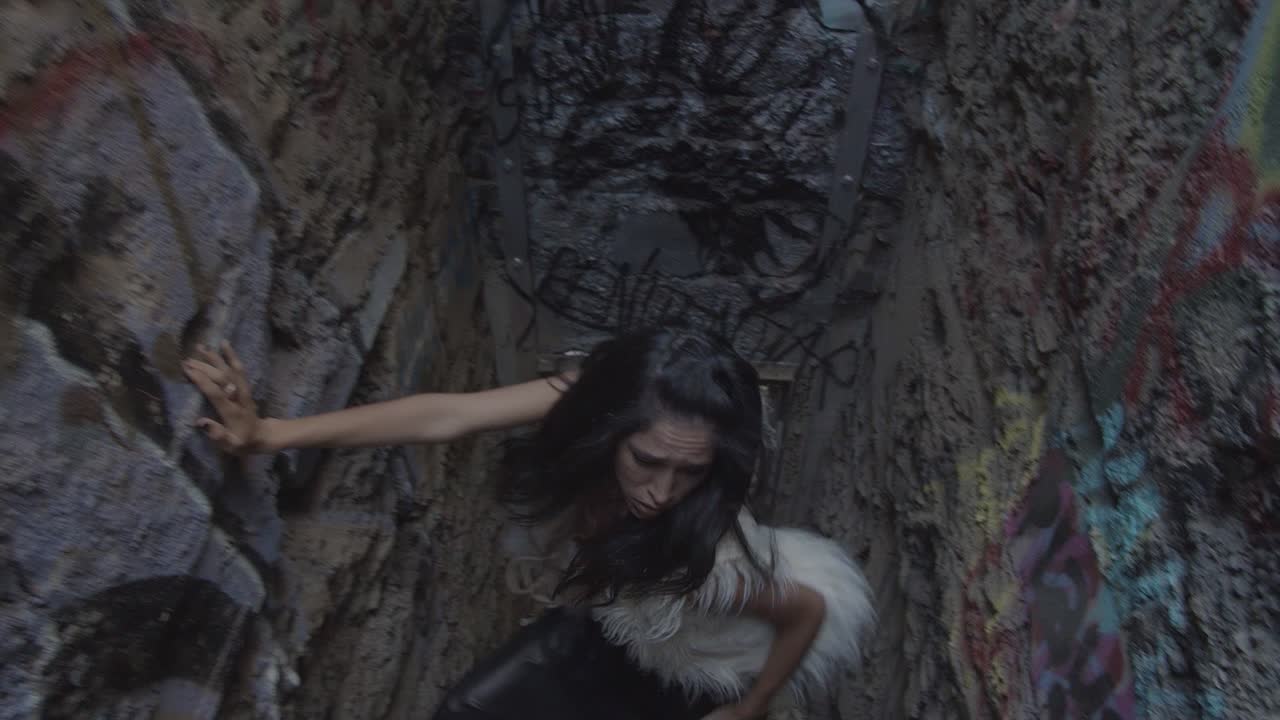 Slow motion shot of a dancer in a white fur vest who flips her hair back in a urban interpretive dance