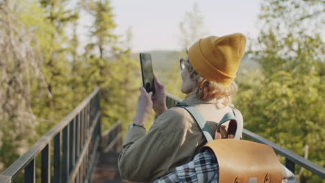 mujer tomando una foto de un paisaje de montaña