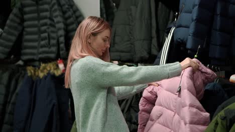 woman is taking a new winter coat from a rack to fit