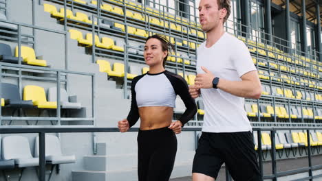 happy sportive couple talking and running together in the stadium 2