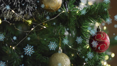 Animation-of-snow-falling-over-christmas-tree-with-baubles