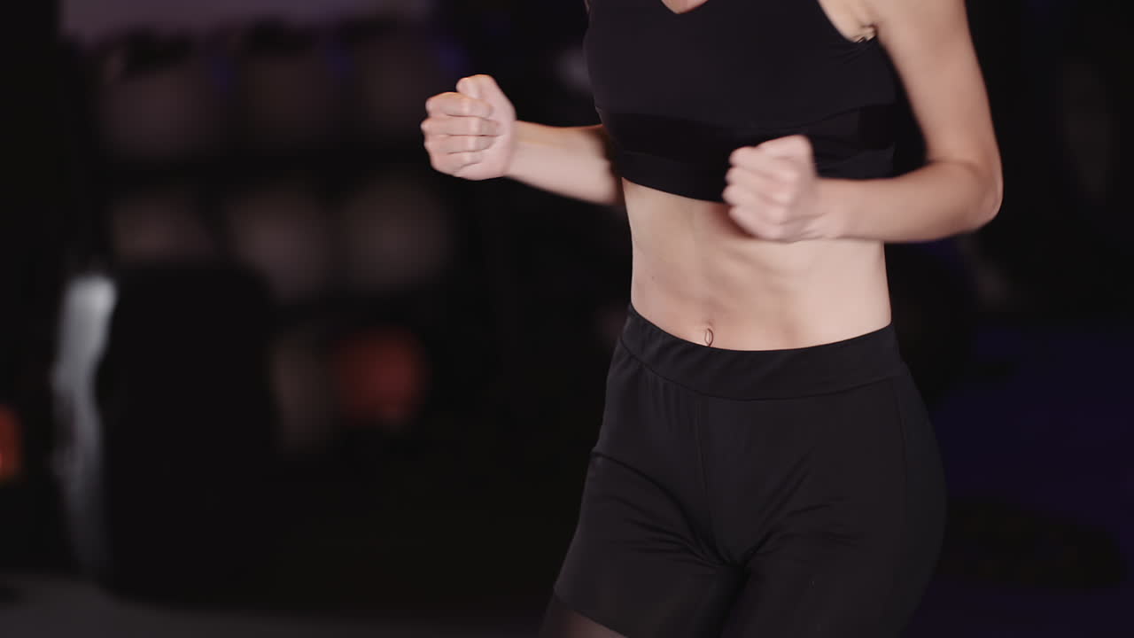 Mezzo busto di giovane donna sportiva che fa jogging sul posto in uno studio fitness