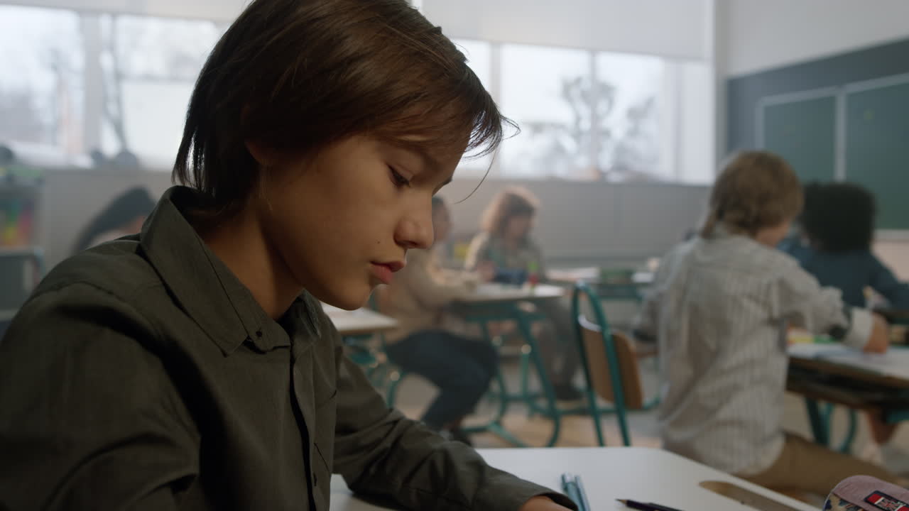Student sitting at desk in classroom during lesson. Boy studying at school
