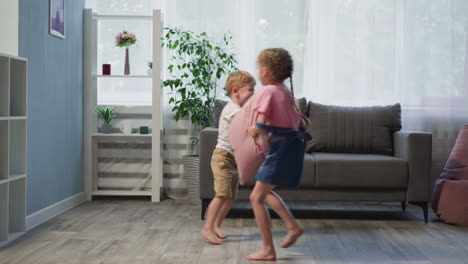 Active-siblings-jump-fighting-with-pillows-in-living-room