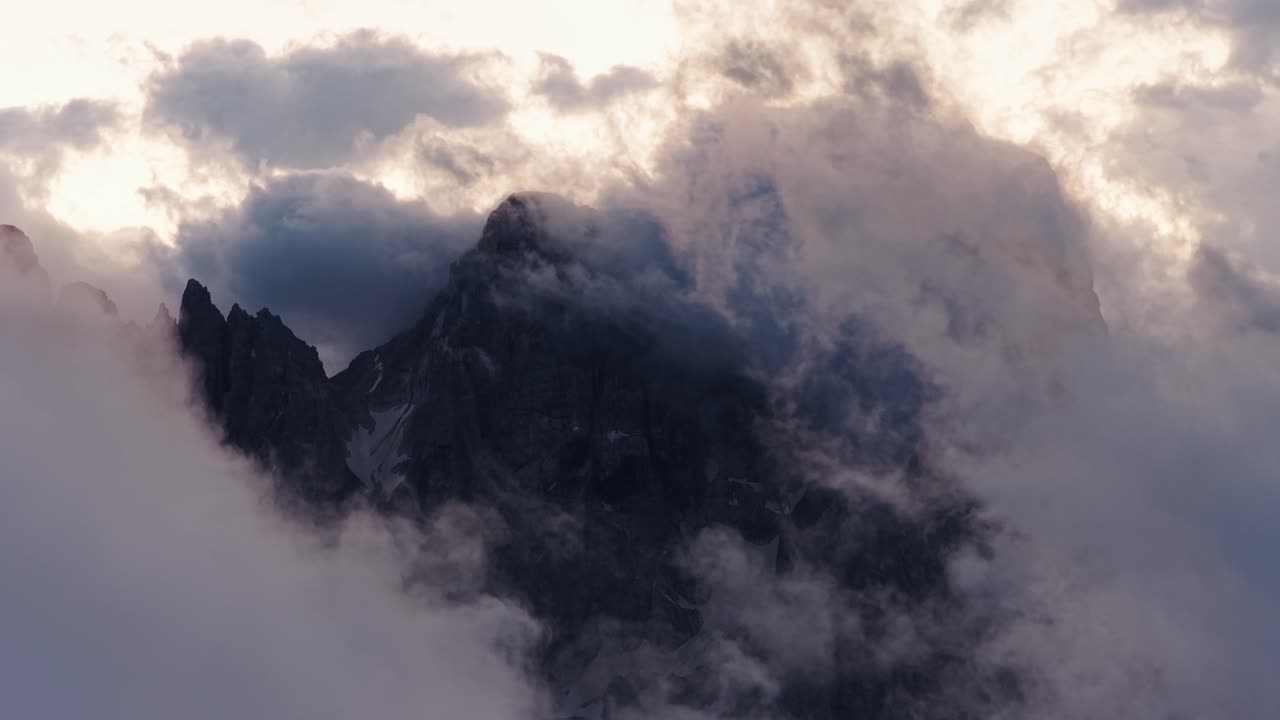 Clouds float around jagged peaks in Pale di San Martino, Italy