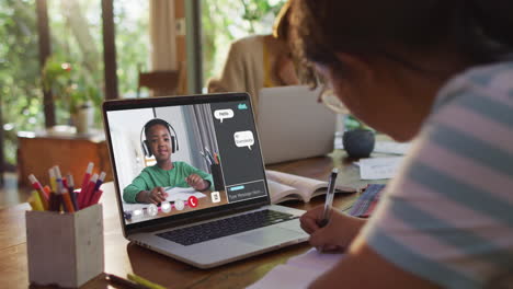 african american girl doing homework and having a video call with classmate on laptop at home