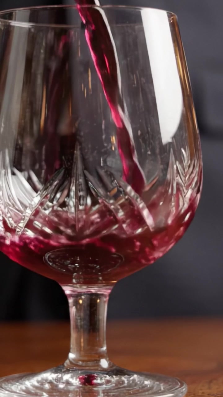 Elegante bicchiere di cristallo con intensi riflessi di vino rosso catturati con dettagli mozzafiato, perfetto per celebrare occasioni speciali e gustare bevande pregiate