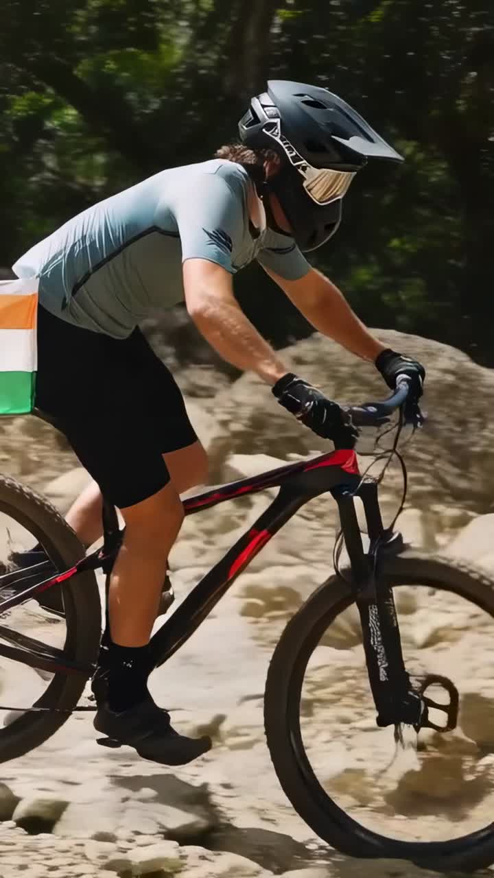 Video verticale: ciclista MTB che alza la ruota per superare le rocce su un sentiero nel bosco, con il casco