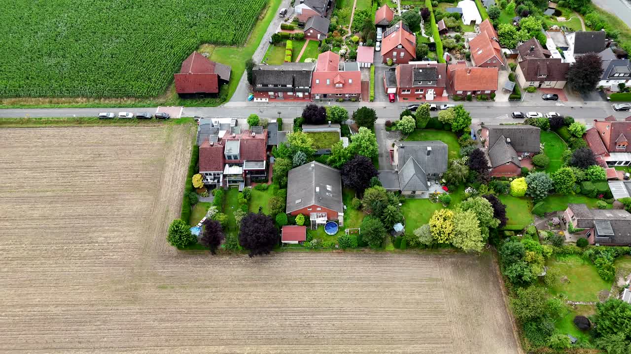 Houses and homes bordering rural farm fields during sunny day in America. Aerial top down shot. Pool in garden. Red tile roof in German city neighborhood