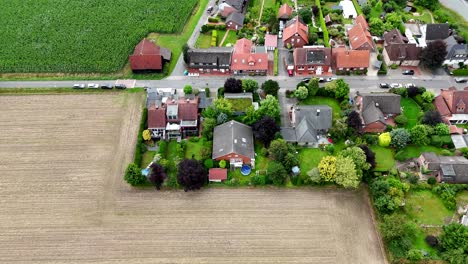 houses and homes bordering rural farm fields during sunny day in america. aerial top down shot. pool in garden. red tile roof in german city neighborhood