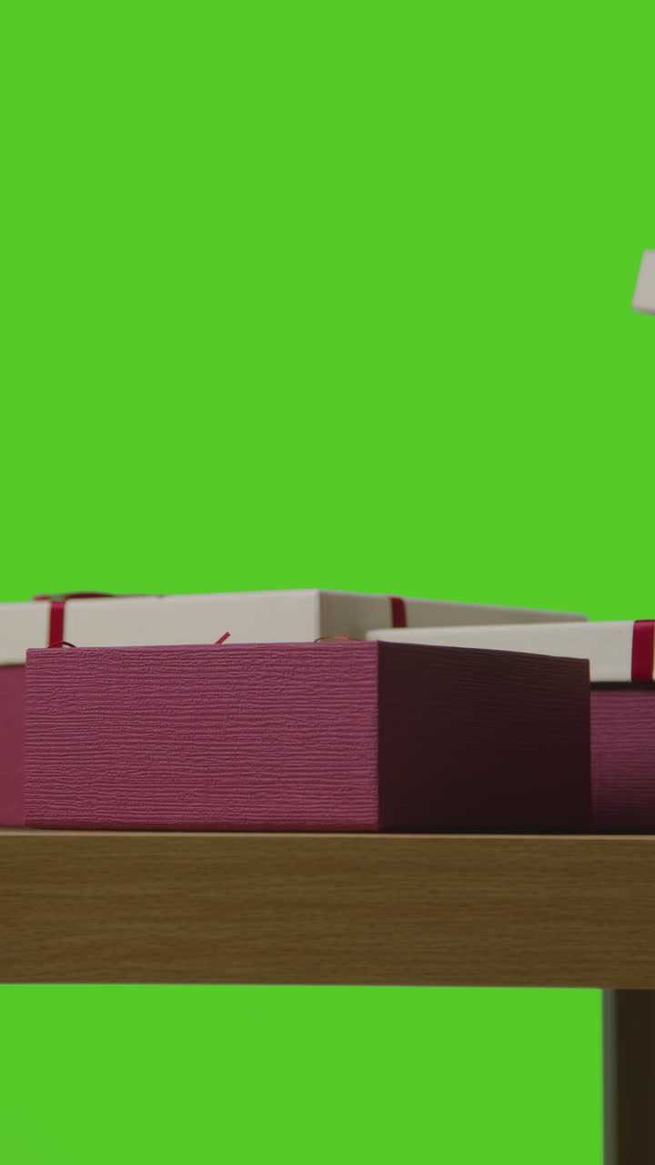 video vertical de un hombre abriendo un regalo en una caja envuelta en una mesa disparado contra una pantalla verde 1