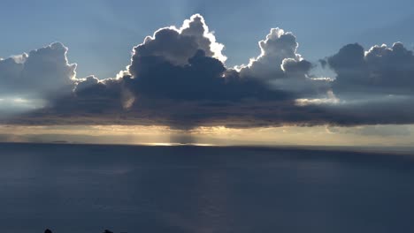 sunset over calm sea obscured by clouds in the sky