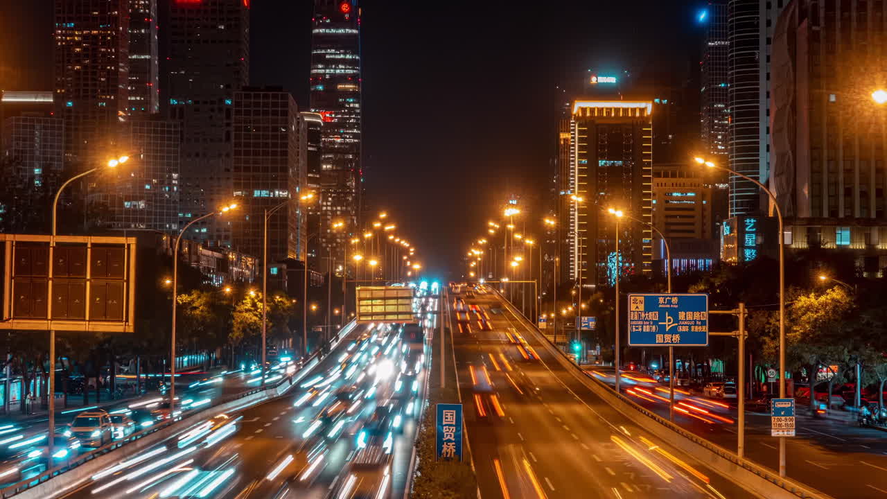 Night view of a busy city highway with light trails from cars and illuminated skyscrapers