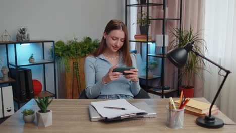 worried young business woman enthusiastically playing racing or shooter video games on smartphone