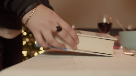 guy picking up the bible during a christmas dinner, handheld, side, close