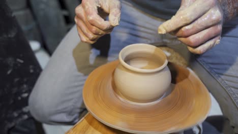 hands shaping clay on a pottery wheel