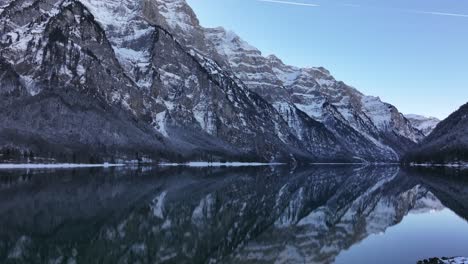 Breathtaking aerial view of Klöntalersee lake on a winter day, with the surrounding mountains perfectly mirrored in the water.