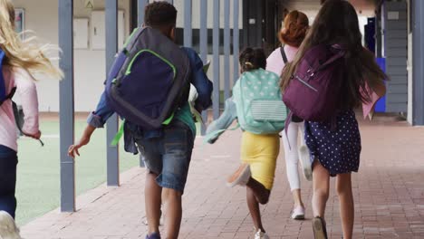 diverse schoolchildren running with school bags together at school