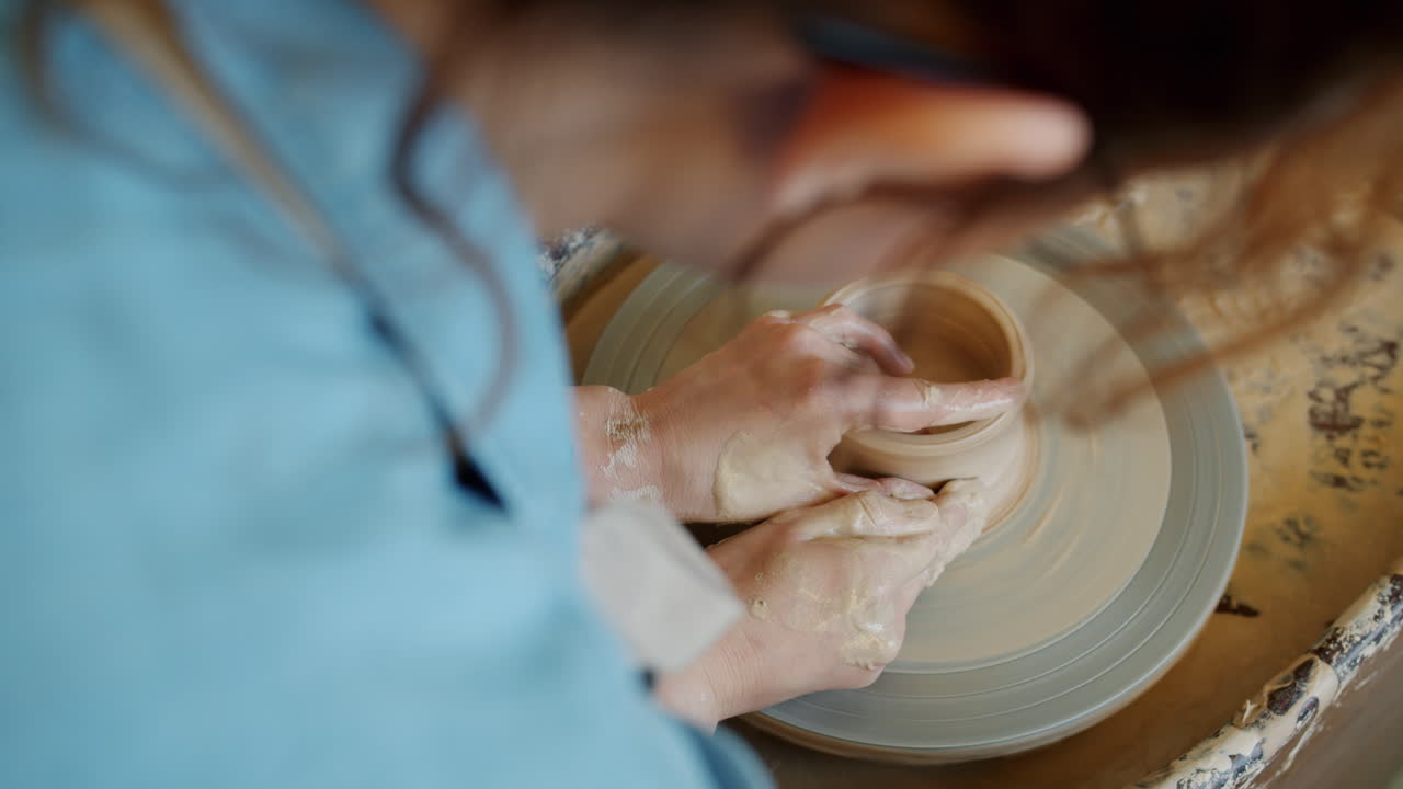 mujer moldeando arcilla en una rueda de cerámica