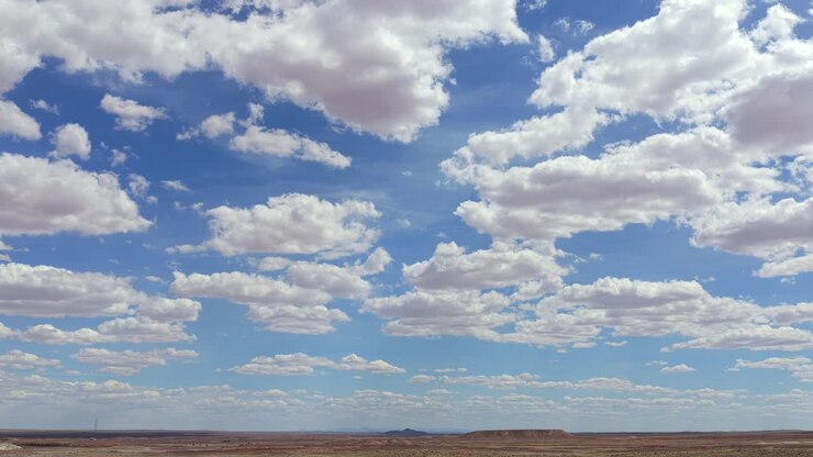 This scenic drone timelapse shows clouds rolling over a rugged southwest horizon in Arizona. The wide-angle view showcases the high desert terrain and changing light in a beautiful nature setting