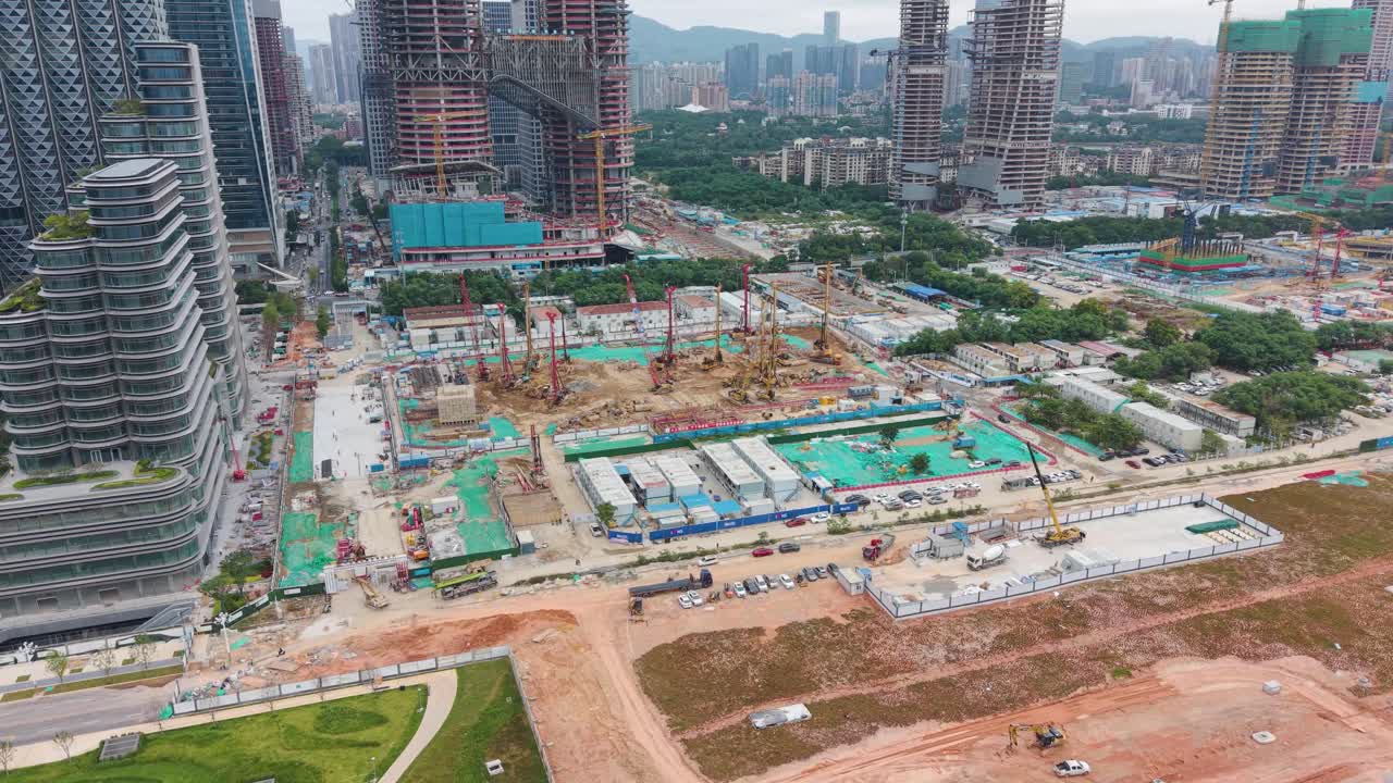 Aerial view of a large construction site in Shenzhen, showcasing cranes, foundations, and rising high-rises as the district rapidly develops into a major banking, finance, and urban hub. China, UHD