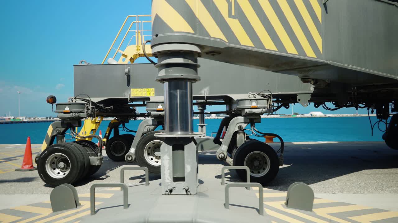 거대한 해상 크레인의 거대한 기둥이 항구를 지배하고 있으며, 상승을 위한 노란색 사다리와 이동을 위한 거대한 바가 있습니다.