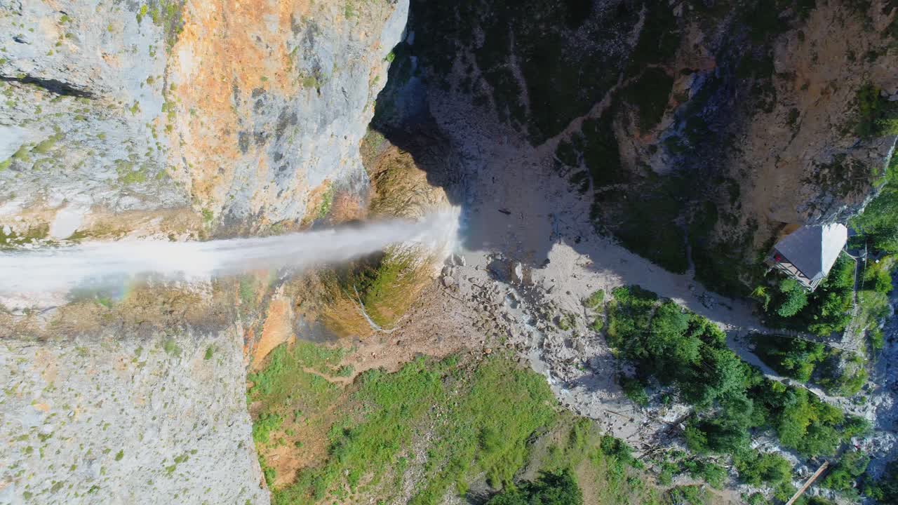Top view of the water of a large waterfall that falls deep into a valley from a cliff. Slow motion panning drone top view