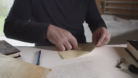 the man signs the letter and puts it in the envelope