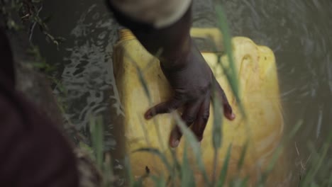 Child-filling-water-container-with-dirty-water-slow-motion-60-frames-per-second