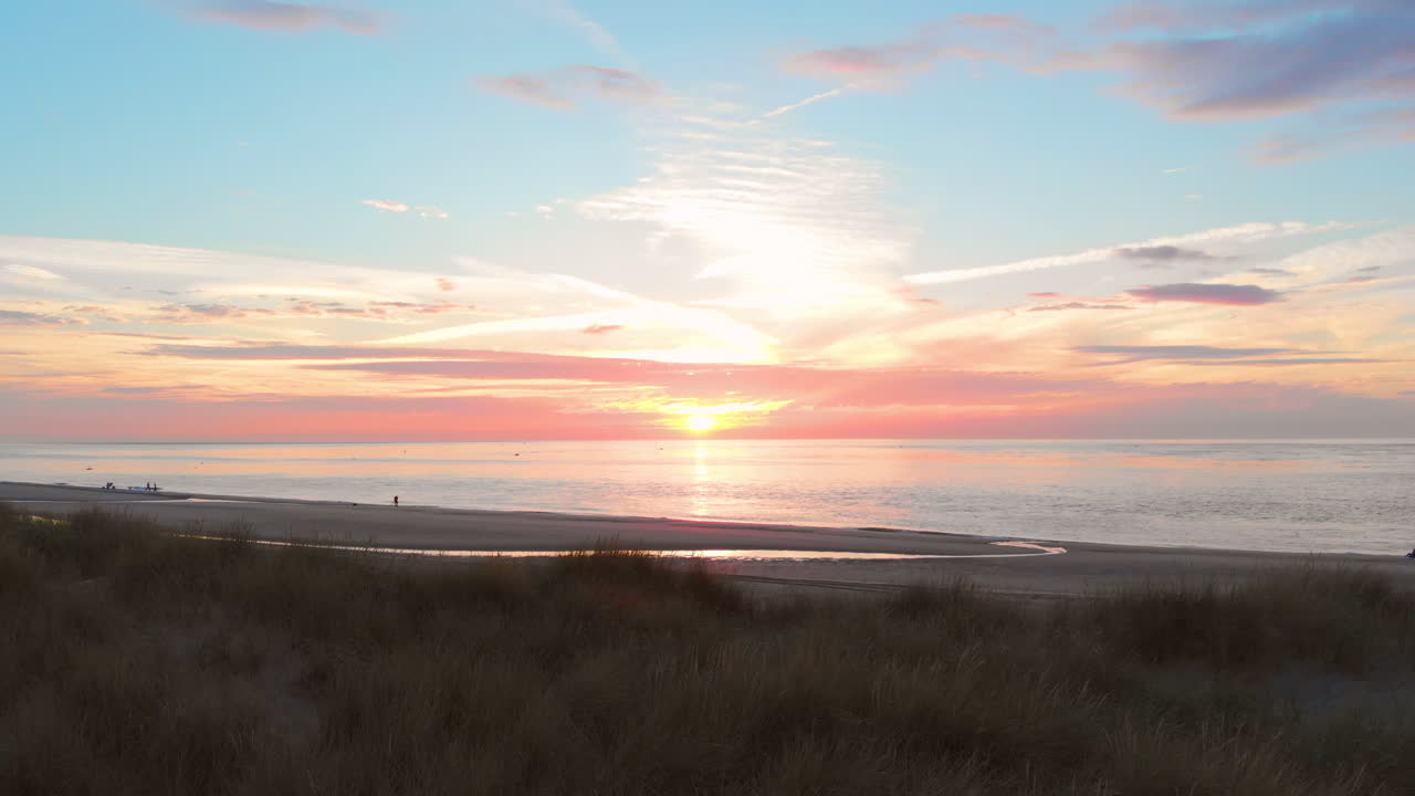 una marea baja tranquila en la playa cerca de la barrera de marejada en el suroeste de los países bajos, durante la puesta de sol