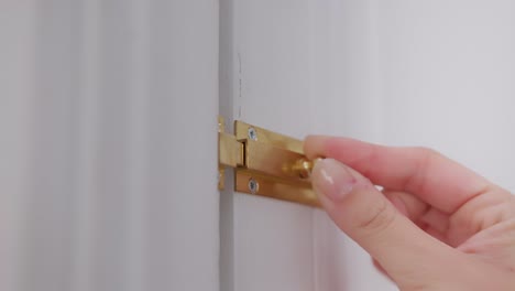 mujer cierra la puerta con un cerrojo de acero inoxidable