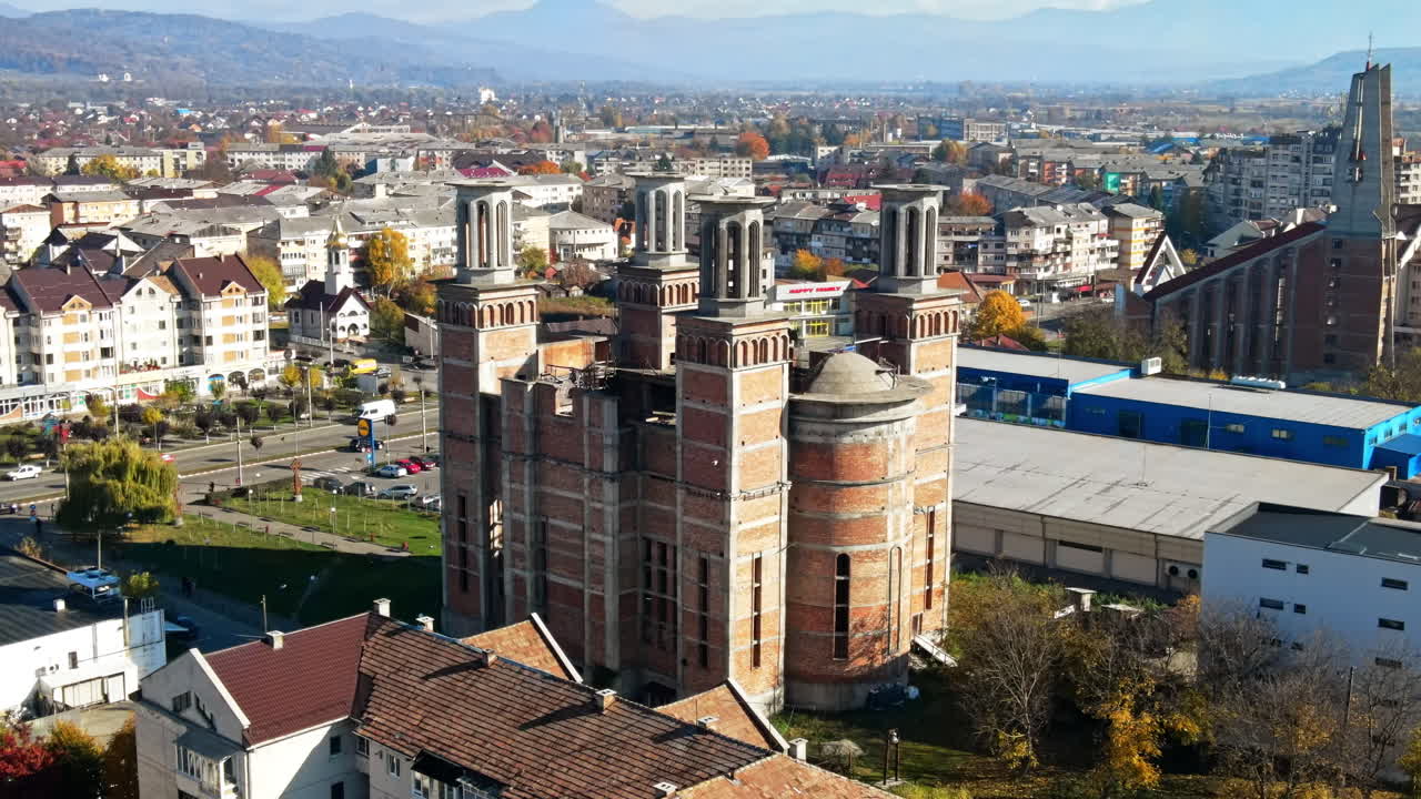 Aerial drone view of The Merry Cemetery in Sapanta, Romania. Church and multiple tombstones, visitors, residential buildings, yellowing trees
