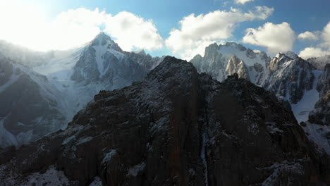 Rotating-epic-cinematic-drone-shot-of-a-mountain-top-surrounded-by-higher-mountains-in-the-Ak-Sai-glacier-in-Kyrgyzstan