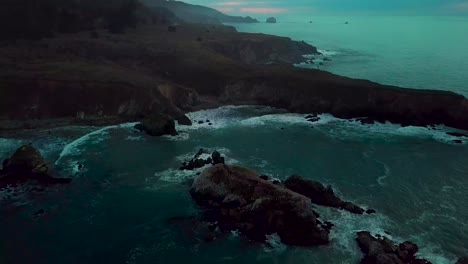 Fast-Dolly-Out-Revela-La-Enorme-Península-Del-Acantilado-Oceánico-Erosionada-Por-Las-Olas-Rompiendo-Al-Atardecer-En-Sand-Dollar-Beach-En-Big-Sur,-California