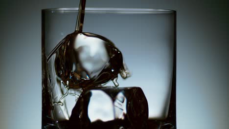 stream of liquor pouring into glass with ice