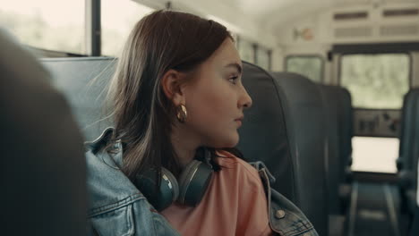 teenage girl sitting school bus close up. schoolgirl chatting with passenger.