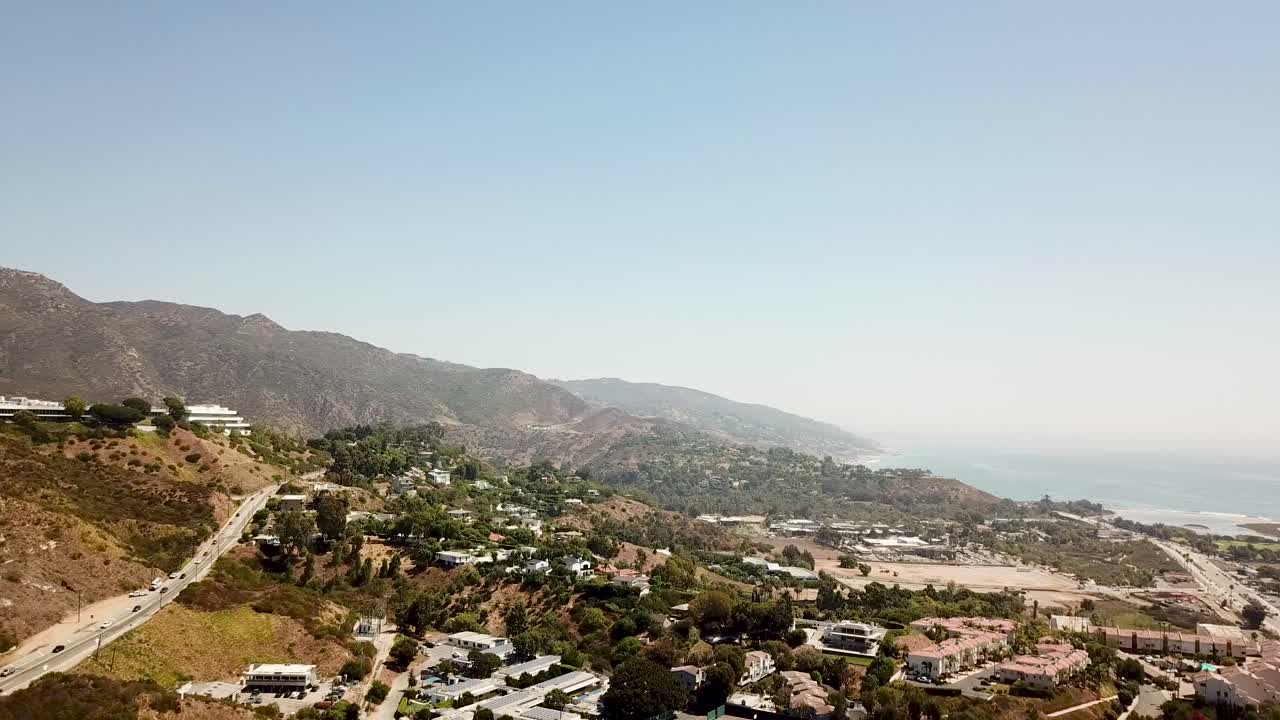 Mountain highway and Pacific coast Highway in Malibu with ocean view. Aerial panning wide shot. California during autumn season. Beautiful landscape with sport field and university.