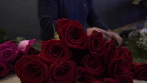 caucasian florist with mask making and selling red and pink roses bouquet for valentine's day for delivery