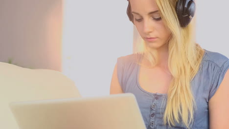 Hermosa-Adolescente-Usando-Una-Computadora-Portátil-En-Su-Sofá-Y-Escuchando-Música