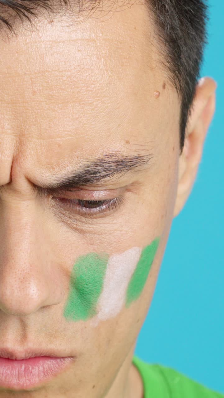 Serious man with a nigerian flag painted on the face