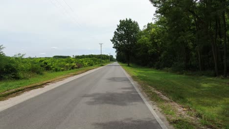 flying over the empty road leading to the rural village in summer