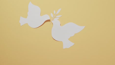 close up of white doves with leaf and copy space on yellow background