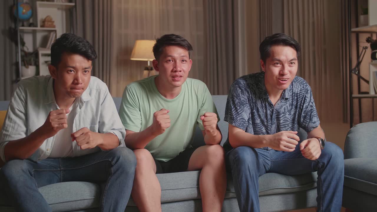 Three friends watching a match on the sofa.